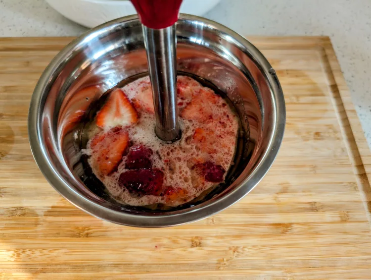 Mélangeur sur pied dans un bol de fraises pour la préparation de la vinaigrette aux fraises