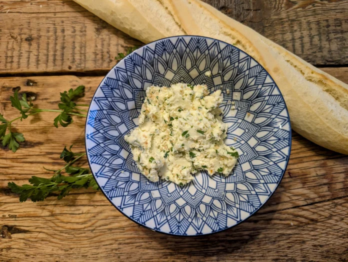Préparation de beurre à l'ail sur une table avec une baguette de pain